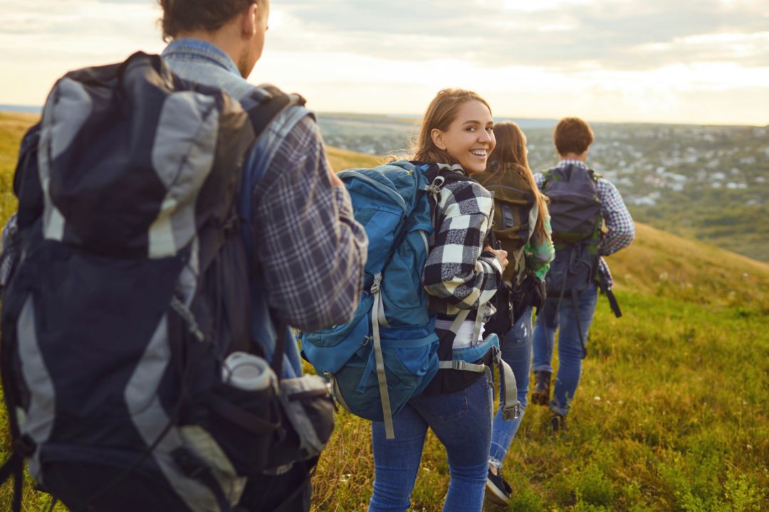 Photo shows a group of young adults hiking in hills above a town