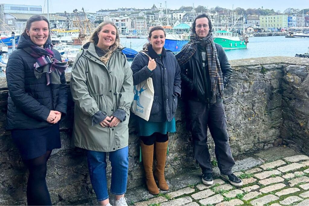 Staff from MLA College pause in front of a harbour scene during their walk for charity with the trundl app