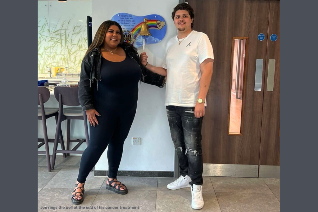 A young man rings the bell to show that he has finished his cancer treatment. His smiling partner stands beside him. Both are members of walking for charity app trundl