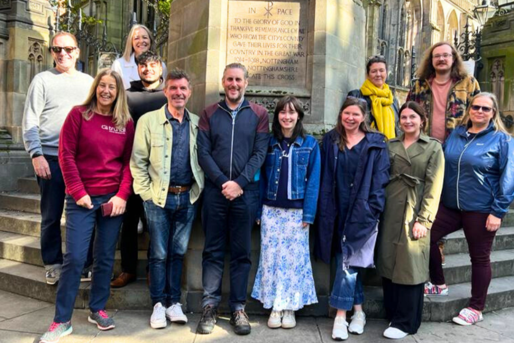 A group of company members of the trundl walking for charity app gather in front of a cenotaph in Nottingham
